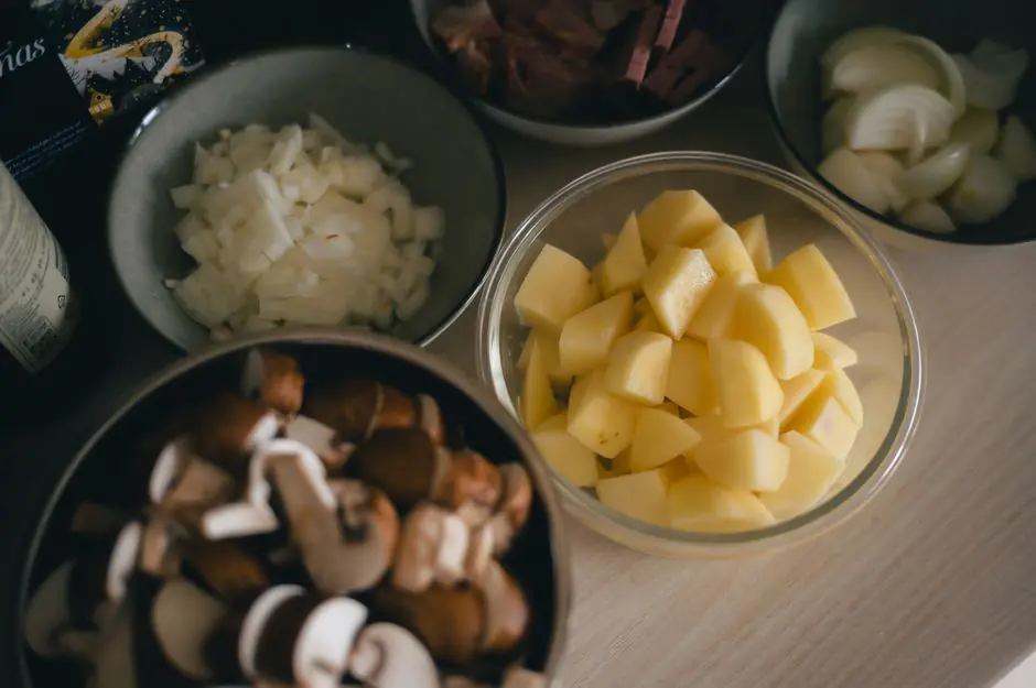 Préparation d'une salade de pomme de terre avec pommes de terre cuites, oignons rouges tranchés et vinaigrette dans un saladier