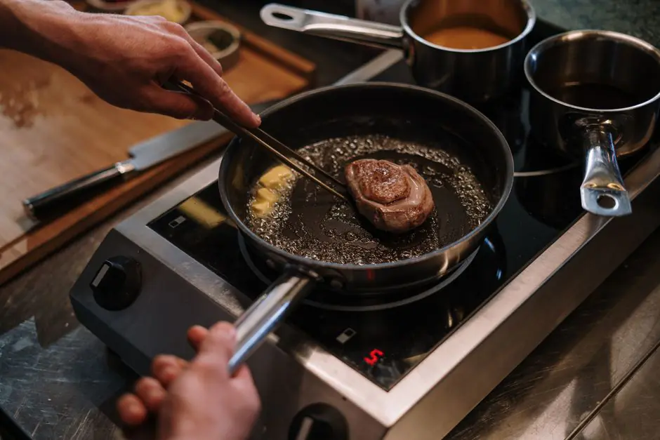 Magret de canard frais posé sur une planche à découper avec des herbes fraîches et du sel